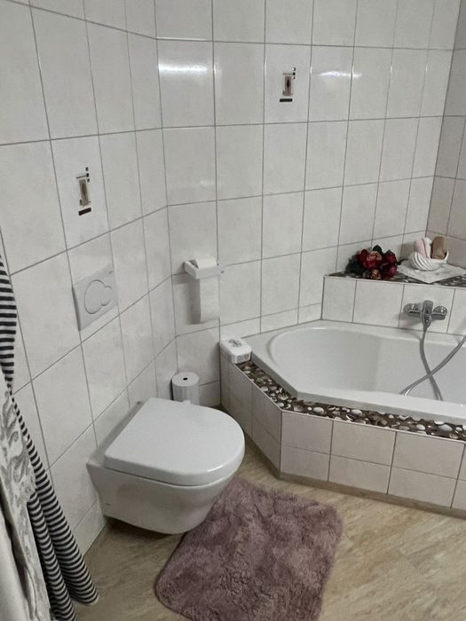Badezimmer vor der Sanierung: altes Eckbadewanne mit gefliesten Wänden