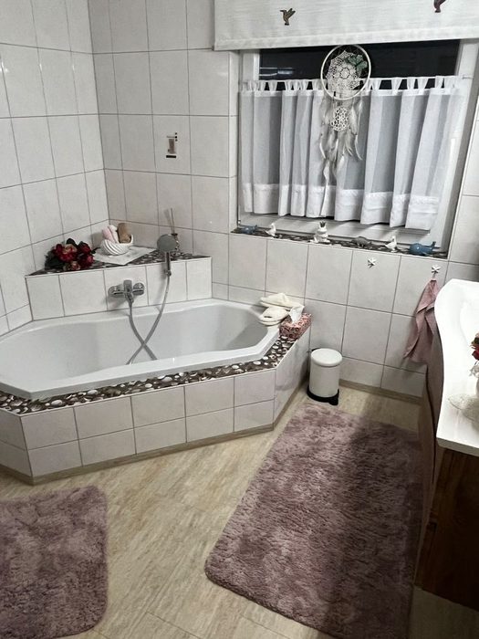 Badezimmer vor der Sanierung: Eckbadewanne mit Fliesenspiegel und Vorhang
